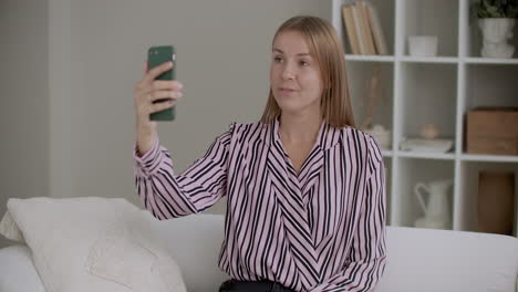 Una-Mujer-Joven-Está-Filmando-Un-Video-De-Entrenamiento-Con-La-Cámara-De-Un-Teléfono-Inteligente-Sentada-En-Casa-Tomando-Selfies